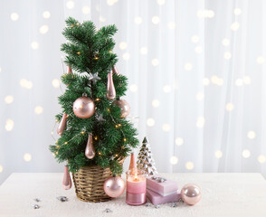 Modern pastel pink color baubles decorations hanging on Christmas tree in home living room, with pink gifts and candle burning. Pastel pink style Christmas concept. Lot of copy space on white.