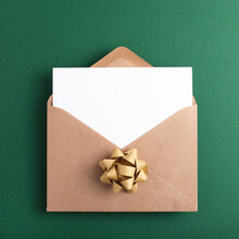 Open Kraft Festive Envelope With Clean Card And Place For Text On Green Background. Flat Lay.