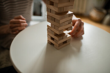 in their free time, two young people concentrate and have fun playing the jenga board game. the hand