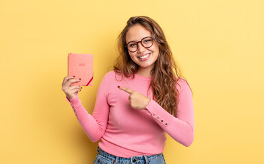 Wall Mural - hispanic pretty woman smiling cheerfully, feeling happy and pointing to the side. agenda concept