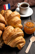 French croissants, coffee and jam on dark background