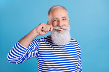 Wall Mural - Portrait of attractive cheerful grey-haired man touching mustache grooming styling isolated over bright blue color background