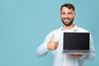 © Prostock-studio - Smiling middle aged caucasian guy show laptop with empty screen and thumb up isolated on blue background