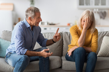 angry senior husband shouting at offended wife having quarrel indoor