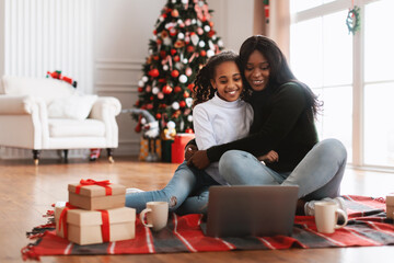 Wall Mural - Portrait of happy black family watching movie on laptop