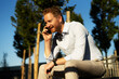 © JustLife - Young stylish businessman sitting on the bench outdoors. Portrait of handsome man talking to the phone.