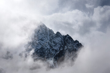 Canvas Print - mountain peaks and slopes in snow in the early morning surrounded by thick clouds