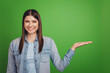 © Tetiana - Photo of young cheerful girl hold hand product offer advert recommendation isolated over green color background