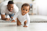 Fototapeta  - Cute Black Infant Baby Crawling At Home, Proud Father Looking At Him