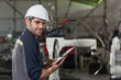 © Supachai - Portrait of male automation engineer smiling hold tablet for .inspection robot arm welding machine  in industrial factory