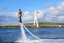 Flyboarding While Using A Jet Ski In Portimao Harbour With Portimao Bridge In The Background.