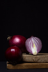 Canvas Print - Red onion on a black background. Red onion cut in half on a board. Onion variety