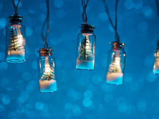 Sticker - Vintage Christmas lights garland. A small Christmas tree in a jar with snow. Blue background