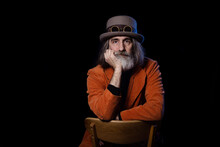 Portrait Of A Stylish Elderly Gentleman In A Steampunk Look. Bearded Gray-haired Man Posing Against A Black Background, The Concept Is An Intellectual Critically Assessing The Situation. 