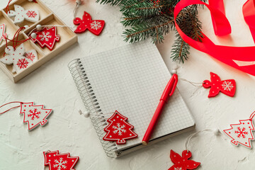 Wall Mural - Christmas composition with a notebook, Christmas wooden toys and red pen on a white background. Copy space.