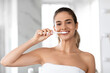 © Prostock-studio - Headshot Of Lady Brushing Teeth Looking At Camera In Bathroom