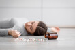 © Prostock-studio - Sad european millennial lady unconscious lying on floor with scattered pills, committed suicide at home