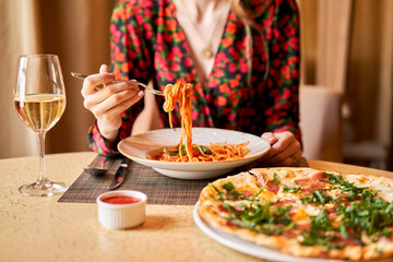 Wall Mural - Woman eats Italian pasta with tomato, meat. Close-up spaghetti Bolognese wind it around a fork with a spoon. Parmesan cheese