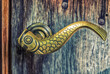 Türklinke aus Messing in der Form eines Fisches an einer alten Holztür
