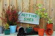 potting shed written on a wooden board hanging on a wood panel door.
