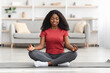 © Prostock-studio - Peaceful black woman meditating alone at home