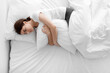 Leinwandbild Motiv Despaired upset sad european millennial woman hugging pillow and lying on white bed in bedrooms, top view