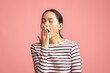 © Prostock-studio - Closeup shot of tired young asian woman yawning over pink background