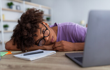 Poster - Sleepy black teenager lying on table near laptop computer, exhausted from online education indoors