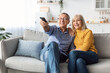 © Prostock-studio - Happy Senior Spouses Watching TV Sitting And Hugging At Home