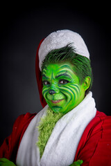 man dressed as christmas green, sitting in studio black background with santa claus suit