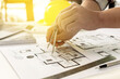 © kamiphotos - Architects, engineers, designers, use compasses to draw on house designs. He is editing the designs that have been created on the program on the computer. Interior design and decoration ideas.