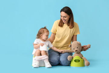 Wall Mural - Mother potty training her little daughter on color background