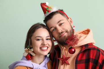 Wall Mural - Happy young couple in stylish winter clothes and with Christmas decor on light background