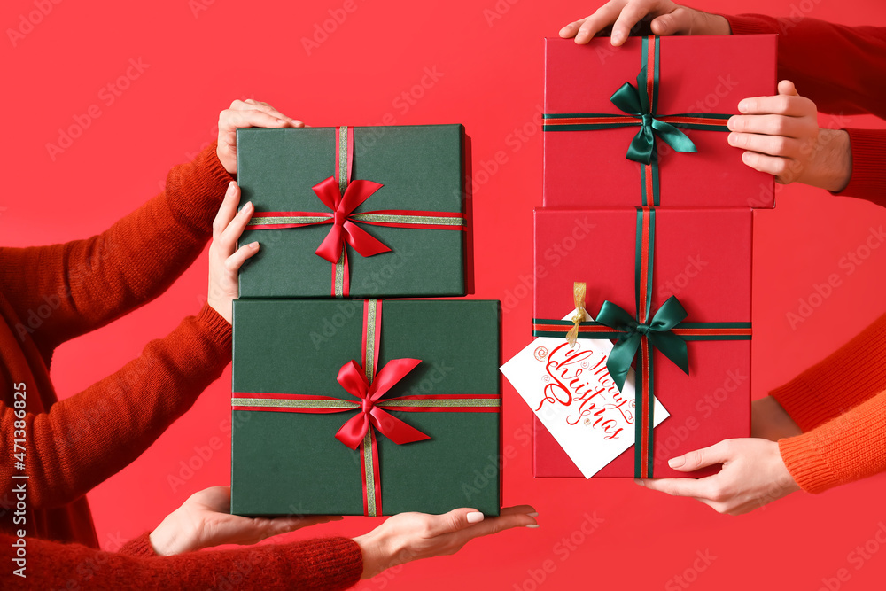Female hands with different Christmas gift boxes on red background