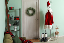 Interior Of Room With Door Decorated For Christmas And Hanger With Santa Claus Costume And Boots Near Color Wall