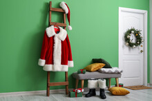 Wooden Ladder With Santa Claus Costume, Boots And Bench With Pillows And Christmas Gifts Near Color Wall