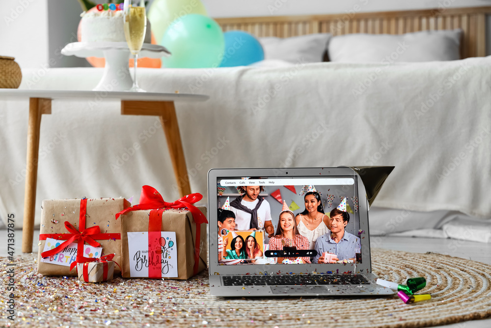 Laptop and gifts on floor in room. Celebrating birthday online due to coronavirus epidemic