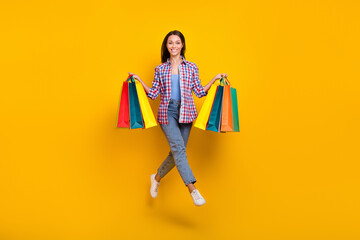 Full length photo of cheerful client lady jump hold store packages wear plaid shirt isolated yellow color background