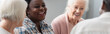 © LIGHTFIELD STUDIOS - Smiling african american woman talking to elderly friends in nursing home, banner