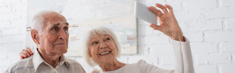 Elderly people smiling while taking selfie in nursing home, banner