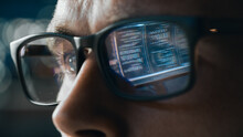 Close-up Portrait Of Software Engineer Working On Computer, Line Of Code Reflecting In Glasses. Developer Working On Innovative E-Commerce Application Using Big Data Concept
