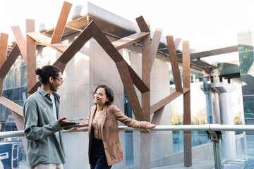 Wall Mural - cheerful woman looking at african american man gesturing while talking to her outdoors