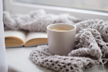 Cozy Home With Cup Of Coffee And A Book. Hygge Style. Mug Of Black Coffee Wrapped In Warm Scarf On Wooden Board. Top View, Vintage Style, Still Life.