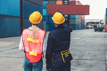 Wall Mural - Industrial worker works with co-worker at overseas shipping container yard . Logistics supply chain management and international goods export concept .