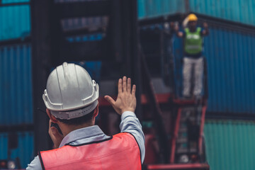 Industrial worker works with co-worker at overseas shipping container yard . Logistics supply chain management and international goods export concept .