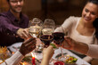 © Syda Productions - holidays, party and celebration concept - multiethnic group of happy friends having christmas dinner at home and drinking wine
