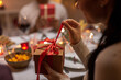 © Syda Productions - winter holidays and celebration concept - close up of happy woman opening christmas gifts at home dinner party