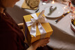 © Syda Productions - winter holidays and celebration concept - close up of happy woman opening christmas gifts at home dinner party