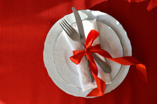 Christmas Table. Cutlery, A Knife And Fork With A Red Ribbon On A White Plate. Background For Christmas And New Year.