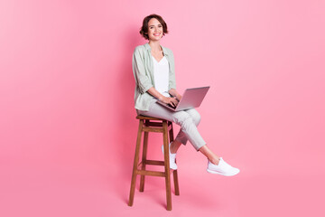 Full size photo of bob hairdo young lady sit laptop wear grey green look isolated on pink background